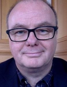 A photo of Joe Little. He is wearing glasses and smiling at the camera.
